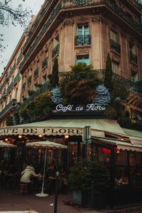 Photo by Jose Vasquez Charming view of Café de Flore with Parisian architecture and vibrant foliage, capturing urban elegance.